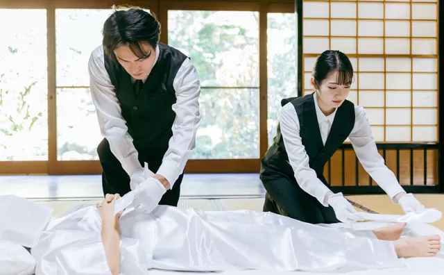 葛飾区メモリーホーム新小岩のスタッフが和室にて白装束を身にまとったご遺体を慎重に清めている様子。