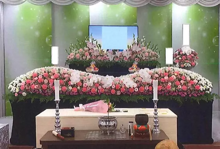葛飾区メモリーホーム新小岩の祭壇の写真。グリーンの背景に赤やピンクの花を飾った華やかな祭壇。