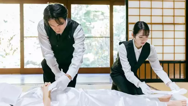 葛飾区メモリーホーム新小岩の葬儀スタッフが和室にて白装束を身にまとったご遺体を慎重に清めている様子。